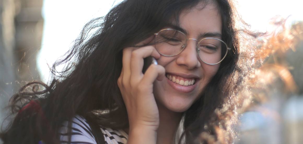 Une jeune femme souriante en train de téléphoner dans la rue